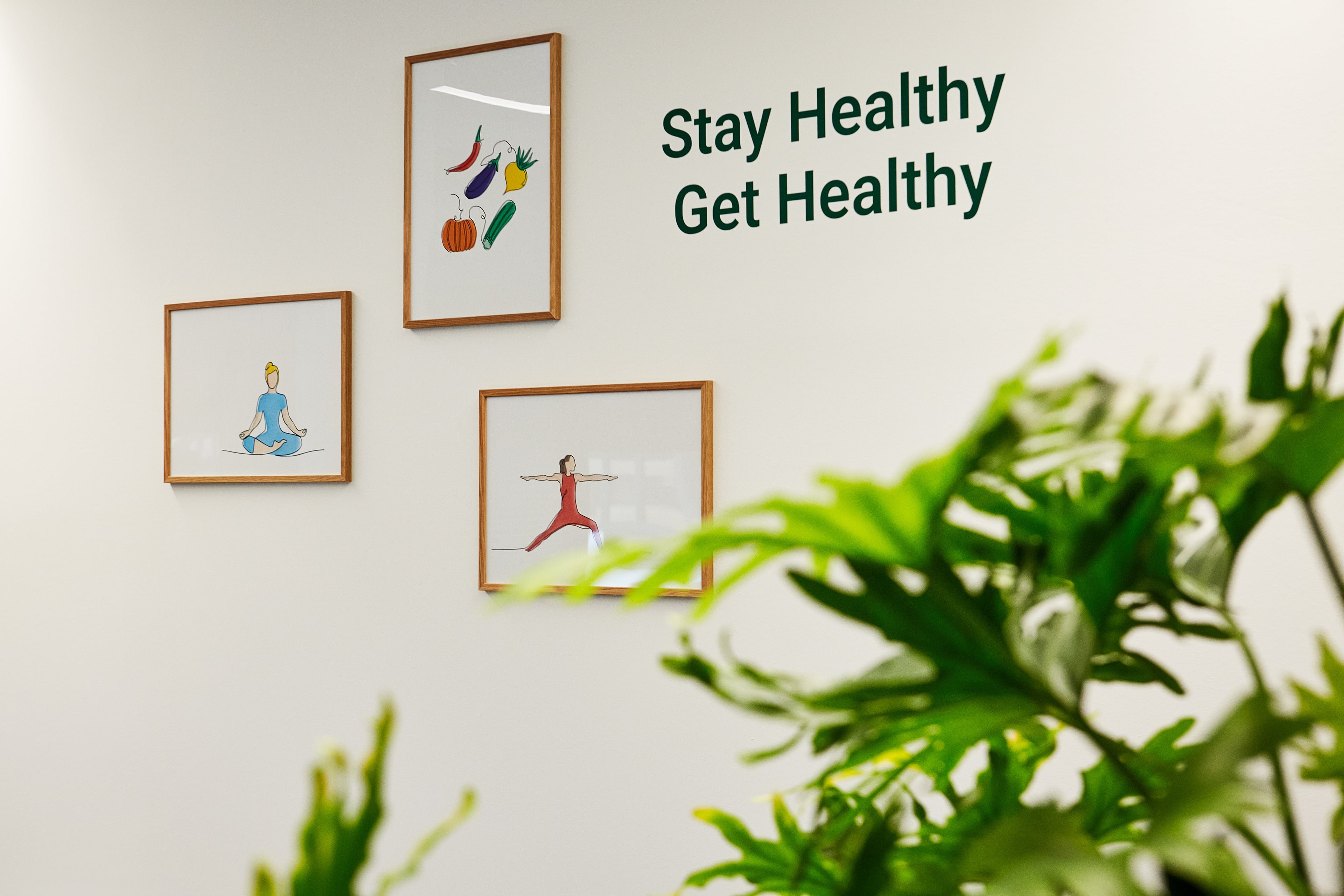 Wand mit inspirierenden Illustrationen zu Ernährung, Bewegung und Achtsamkeit sowie dem Schriftzug ‚Stay Healthy Get Healthy‘.