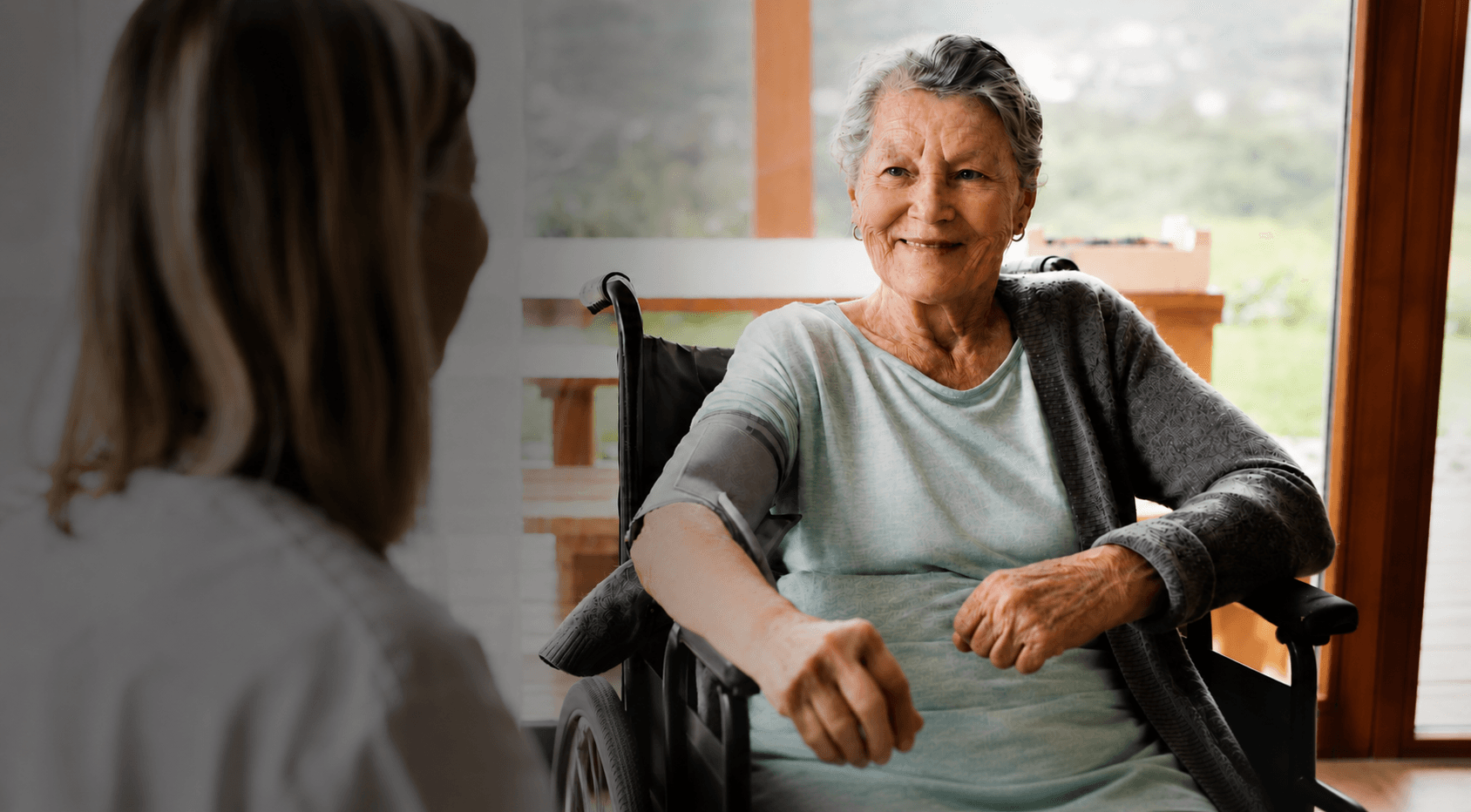 Healthcare professional measuring the blood pressure of an elderly woman during a home care visit.