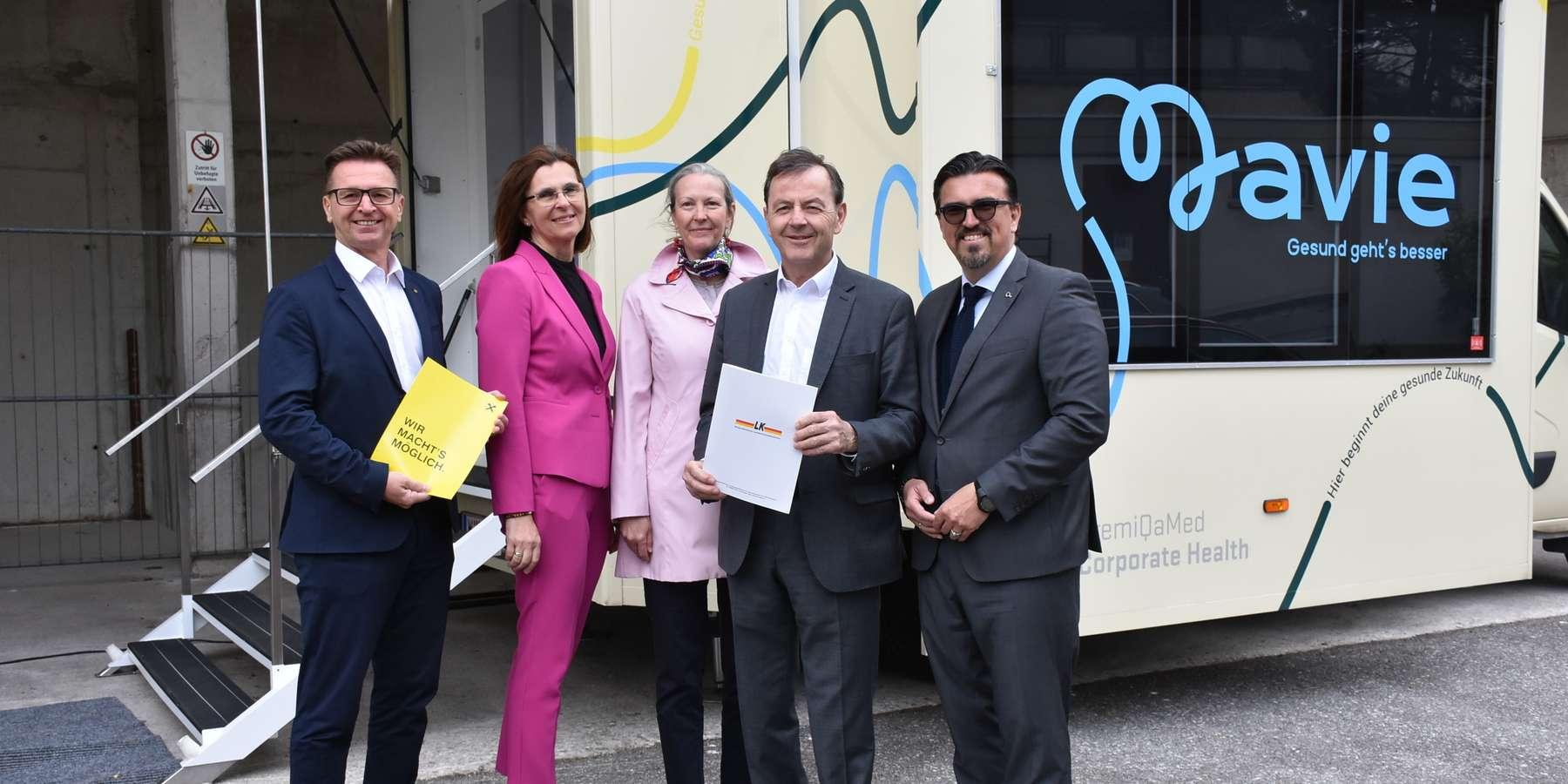 Iko Burgenland Fünf Personen stehen vor dem Mavie Health Mobil und halten Dokumente in der Hand. Die Gruppe wirkt offiziell und geschäftlich – möglicherweise anlässlich einer Kooperation oder Präsentation.